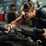 auto-mechanic-using-jumper-cables-while-repairing-car-engine-in